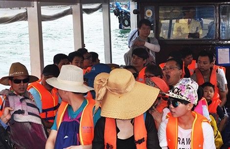 Một hướng dẫn viên người Trung Quốc (đứng sau cùng) đang thuyết trình cho một đoàn khách Trung Quốc tại bến tàu Cầu Đá, TP Nha Trang (Khánh Hòa). (Ảnh chụp sáng 29-6) Ảnh: Tấn Lộc.