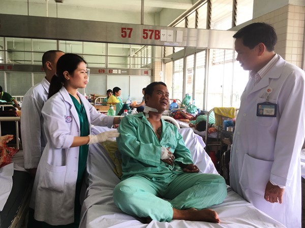 ác sĩ Hoàng Bá Dũng và Dương Thị Thanh Mai hỏi thăm bệnh nhân sau ca mổ lấy đầu đạn (ảnh K.Q)