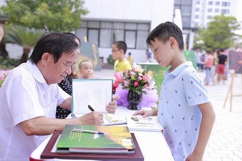  Giáo sư Nguyễn Lân Dũng đang kí tặng lên sách cho một độc giả nhí