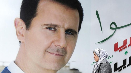 Một người phụ nữ đang đi qua bức chân dung Tổng thống Assad ở thủ đô Damascus