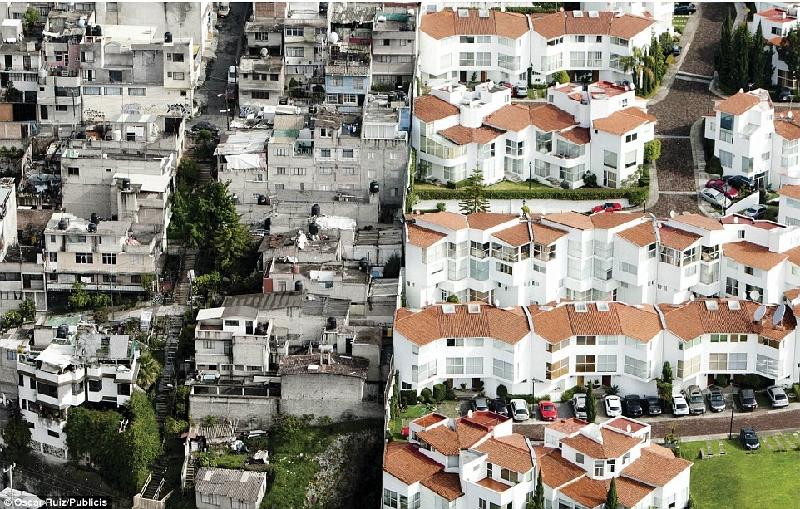 Những khu nhà ổ chuột cũ nát (bên trái) nằm sát cạnh khu biệt thự của các cư dân giàu có ở phía bên kia hàng rào (bên phải) tại Mexico. Ảnh: 