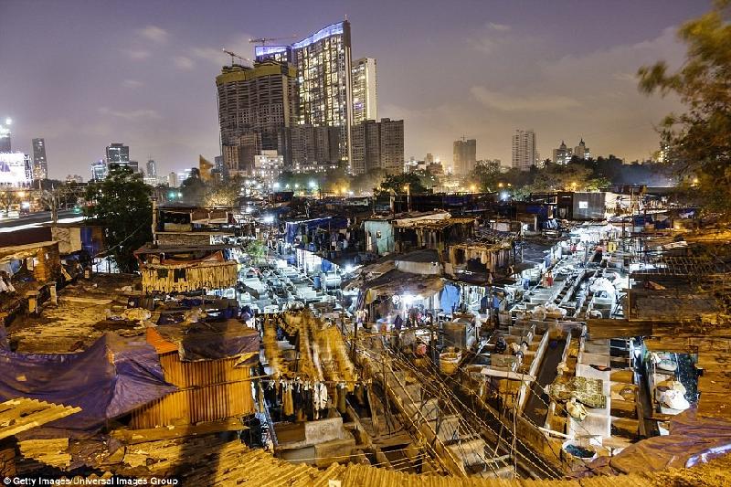 Dhobi Ghat là khu giặt giũ ngoài trời nổi tiếng ở Mumbai, Ấn Độ, nơi quần áo từ các khách sạn, đại sứ quán và các tiệm làm đẹp gần đó được đưa đến để được làm sạch. Người lao động ở đây làm việc cực nhọc cả ngày lẫn đêm trong điều kiện khổ sở và khung cảnh lộng lẫy xa hoa của các tòa nhà cao tầng ngay phía sau họ. Ảnh: 