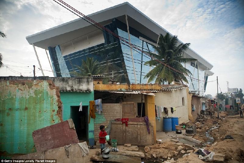 Toà nhà ốp kính mới được xây dựng nằm ngay bên cạnh khu ổ chuột của Bangalore ở Ấn Độ. Xã hội người giàu và người nghèo tồn tại sát cạnh nhau nhưng cuộc sống của những cư dân trong đó thì dường như không bao giờ lẫn lộn. Ảnh: 