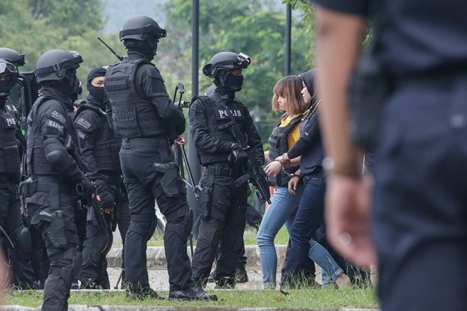 Cảnh sát bảo vệ nghi phạm Đoàn Thị Hương khi cô ra tòa ngày 1/3. Ảnh: AFP.