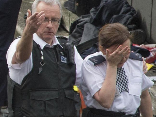 Hai cảnh sát Anh tại hiện trường vụ lao xe ở London hôm 22-3. Một trong hai người không có súng. Ảnh: AP