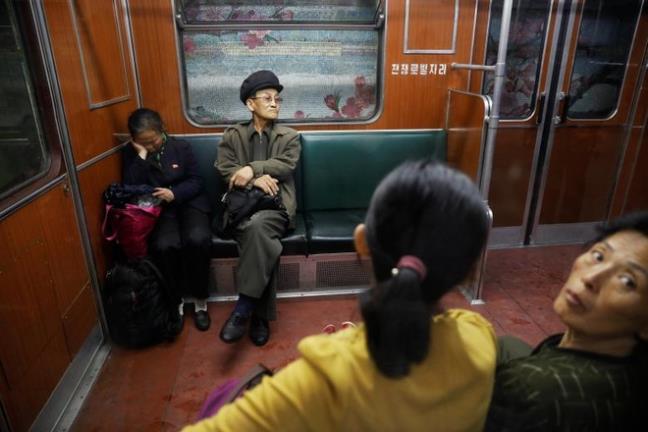 Bà lão ngồi chăm chú nhìn cái ô, còn ông lão ngắm mọi người trong khoang tàu điện ngầm cũ. Một phụ nữ ngoái cổ nhìn phóng viên nước ngoài chụp ảnh.