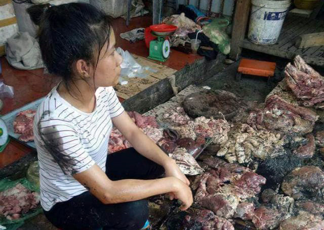 Chị Xuyến ngồi trước khoảng một tạ thịt bị đổ chất bẩn. Ảnh: Facebook.