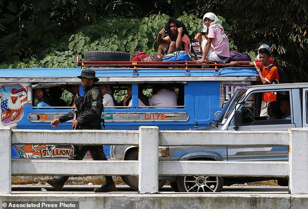 Người dân trèo lên nóc ô tô tải chở người đi sơ tán khỏi cuộc đụng độ trong thành phố.