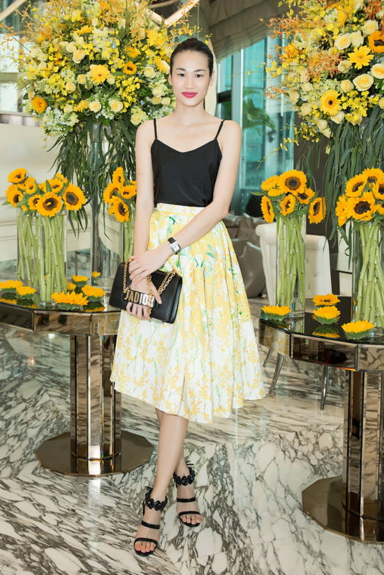 Fashionista Trương Thanh Trúc dung hoà sắc hoa vàng rực rỡ của Adrian Anh Tuấn bằng áo lụa hai dây màu đen kết hợp phụ kiện đồng điệu sắc đen.