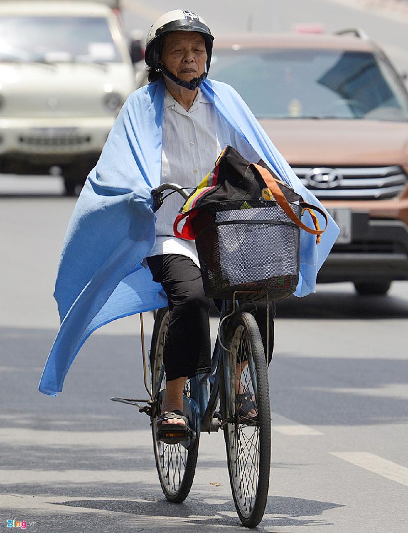 Ra đường giữa trưa là một cực hình đối với nhiều người. Một cụ bà đạp xe trên phố Liễu Giai phải choàng khăn khổ lớn che nắng. Ảnh: Lê Hiếu.