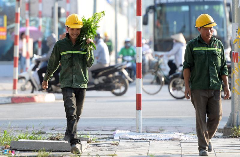 Anh Nguyễn Văn Sang (công nhân thi công một tòa nhà trên đường Trần Duy Hưng) phải dùng tán lá của cành cây bên đường để che nắng khi đi bộ về nghỉ trưa từ công trường. Ảnh: Quỳnh Trang.