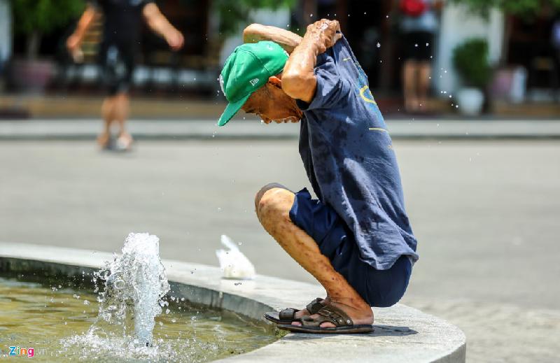 Giữa trưa nắng, một người đàn ông vốc nước trong đài phun vào khắp người để xoa dịu cái nóng lên tới hơn 40 độ C. Ảnh: Nam Nguyễn.