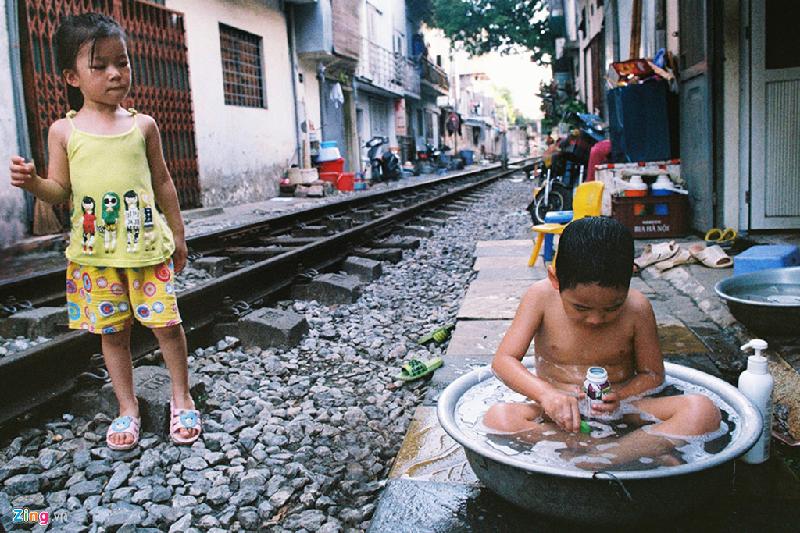 Trong bóng râm trên phố đường tầu (Phùng Hưng), một em nhỏ ngâm mình tắm mát trong chậu nước. Ảnh: Hiếu Trần.