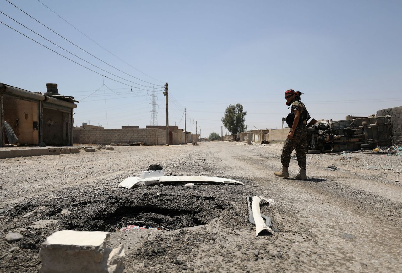 Chiến binh SDF đi qua một hố bom (Ảnh: Reuters)