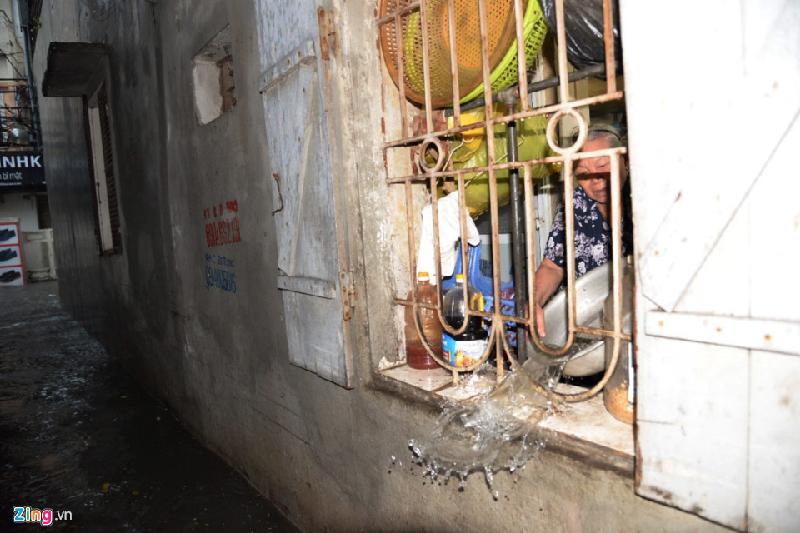 Bà Trần Thị Tươi (nhà số 32 Vũ Trọng Phụng) đóng kín cửa chính để dùng chậu múc nước tràn vào nhà hắt ra ngoài cửa sổ. Ảnh: 