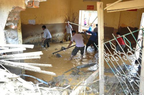 Thày cô giáo và phụ huynh học sinh dọn dẹp phòng học bị đất đá vùi lấp tại trường Tiểu học - THCS Thị trấn Mù Cang Chải. Ảnh: Đinh Hữu Dư/TTXVN