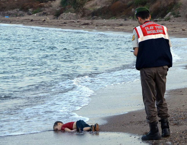 Bức ảnh một em bé chết trên bờ biển tại Bodrum, Thổ Nhĩ Kỳ đã khiến cả thế giới bàng hoàng, giật mình nhìn lại. Em bé xấu số đó là Aylan Kurdi, 3 tuổi, đến từ thị trấn Kobahi phía bắc Syria, nơi đã diễn ra những cuộc chiến tranh trong suốt 4 năm qua. Aylan, bố mẹ, anh trai lên 2 chiếc thuyền cùng 19 con người khác rời bỏ quê hương Syria đi tìm một miền đất mới. Nhưng chiếc thuyền quá tải đã bị chìm mang theo sinh mạng của 12 người khác trong đó có Aylan. Em nằm trên bãi biển, giống như một thiên thần nhỏ đang say ngủ. Nhưng thiên thần nhỏ sẽ không bao giờ tỉnh lại.