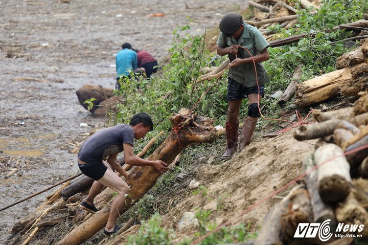 Những khối gỗ rất nặng, người dân phải dùng dây, thậm chí cần 2,3 người mới có thể mang được gỗ lên bờ. (Ảnh: Phong Sơn)