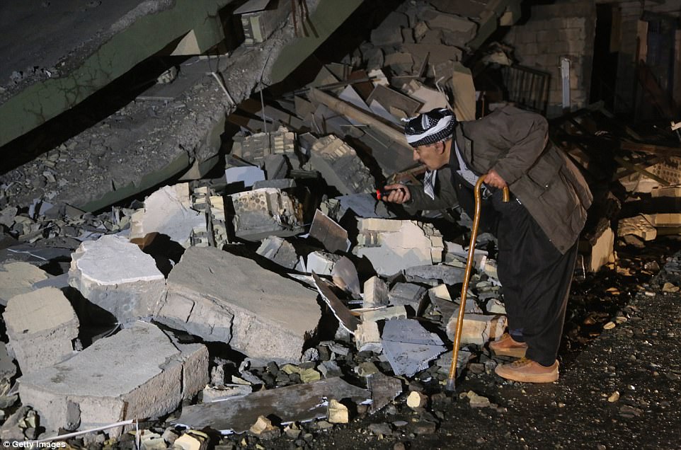Một người dân đang cố tìm kiếm những gì còn lại sau khi ngôi nhà của họ bị sập đổ hoàn toàn