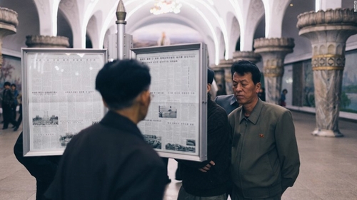 Mọi người chăm chú đọc các tờ báo được dán trong cột bản tin ở trạm điện ngầm trong lúc chờ tòa. Ảnh CNN