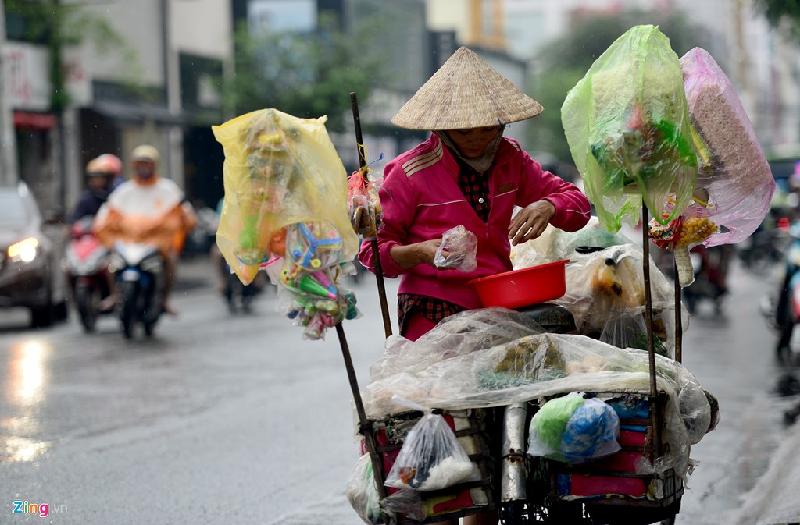 Tuy mưa không lớn nhưng cũng ảnh hưởng đến việc mưu sinh của nhiều lao động nghèo. Phần lớn những người làm nghề bán hàng rong đều phải vừa che, bọc hàng hóa của mình vừa bán hàng trên đường phố.