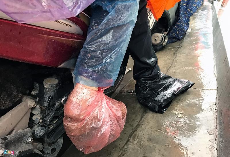 Trên đường xuất hiện nhiều vũng nước đọng có thể gây bẩn quần, giầy, tất cho người đi xe máy. Để đối phó với tình trạng này một số người đã bọc nilon vào chân để đảm bảo sạch sẽ khi tới nơi làm việc.