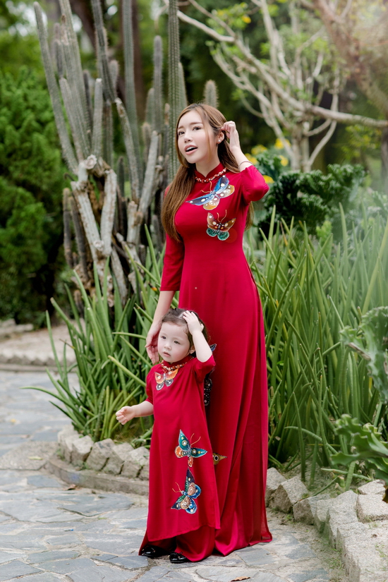 Nếu bộ cánh của Elly Trần được chiết may ôm sát, thể hiện đường cong mềm mại thì tà áo Cadie diện có kiểu dáng xinh xắn. Nền vải được điểm xuyến bằng nhiều hoạt tiết thêu thủ công, kết hợp cùng in hoa văn bắt mắt. Đặc biệt, chuỗi vòng cổ hạt càng khiến thiên thần nhỏ Cadie Mộc Trà trông như đúc một phiên bản nhí của mẹ Elly Trần.