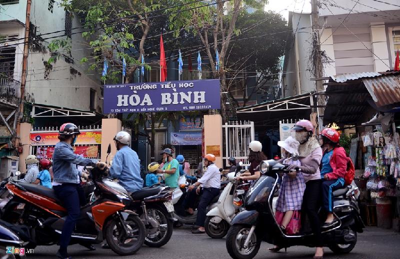 Nằm ngay giữa chợ, trường Tiểu học Hòa Bình bị bao vây bởi các sạp hàng. Thời điểm tan trường, nhiều phụ huynh đứng tràn trước cổng, chen chúc trong chợ để đón con em.