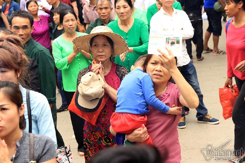 Vừa bế cháu vừa vái vọng trước cửa đền