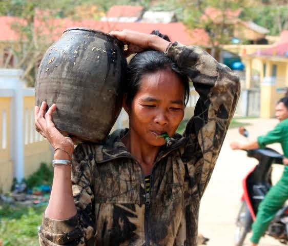 Phụ nữ A Rem với ché rượu đoác mang từ trong rừng về