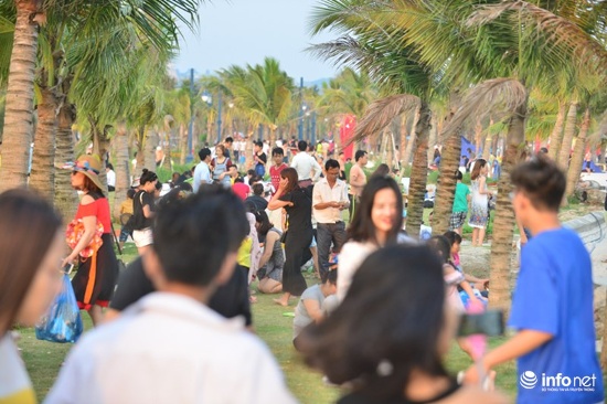 Trên bờ, từng đoàn người ngồi kín khắp bãi cỏ quanh bờ biển
