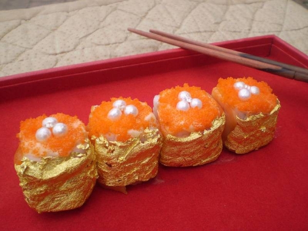Những miếng sushi dát vàng không được tạo ra tại quê hương Nhật Bản mà là tác phẩm của đầu bếp Philippines Angelito Araneta Jr. 5 miếng sushi với giá 1.800 USD được tạo nên bởi các nguyên liệu dấm balsamic Ý, gạo Nhật Bản, đường Muscovado, cá hồi hồng Na Uy. dưa chuột biển, xoài, cua, nghệ tây hoang dã và bơ mayonnaise. Thứ tạo nên mức giá 