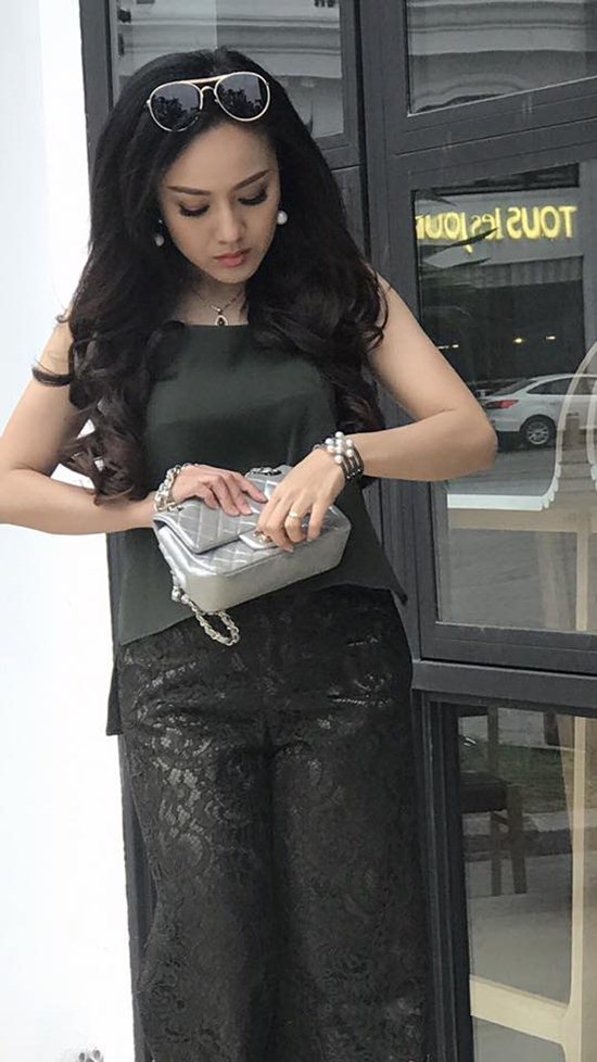 Trang phục dạo phố gồm áo liền quần ren xuyên thấu màu xanh rêu rất trang nhã. Để hoàn thiện set đồ, Hoài Anh làm điệu bằng túi màu xám bạc của nhãn hiệu túi ưa thích của cô là Chanel, kết hợp với dây đeo tay dạng vòng ngọc trai to, trang sức cổ và kính râm cài tóc.  