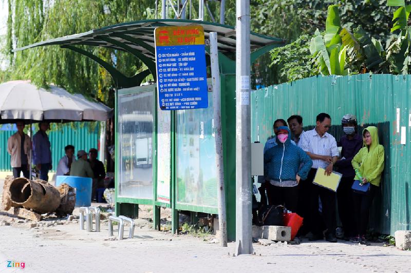 Hành khách đi xe buýt trốn nắng, chui tạm vào bóng râm phía sau nhà chờ xe trên đường Phạm Hùng. Ảnh: Thế Đại.