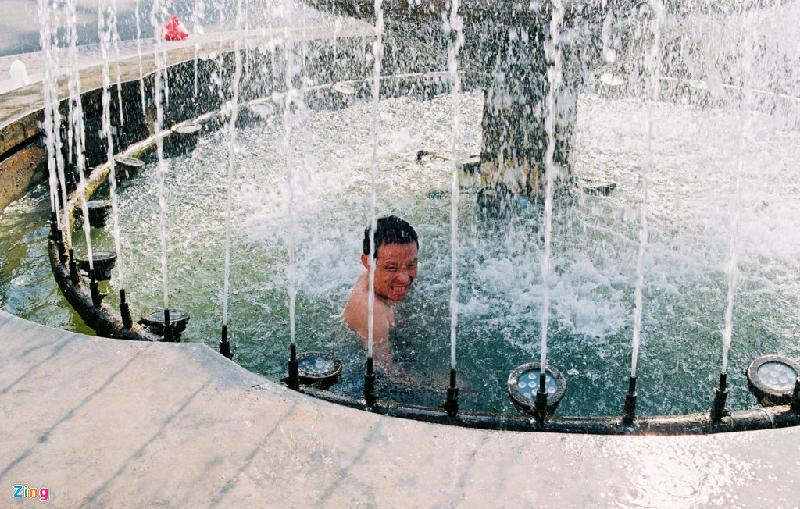 Thậm chí có người đàn ông nhảy vào đài nước để giải tỏa cơn nóng bỏng da bỏng thịt trên phố. Ảnh: Thành Thế Vinh.