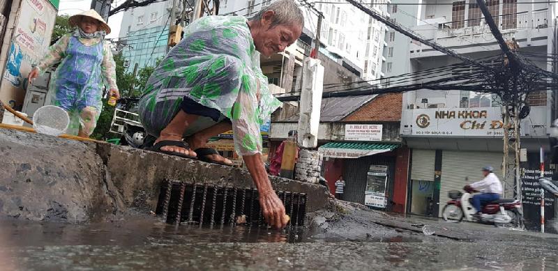 Người Sài Gòn vô tư ngồi uống trà sữa giữa biển nước sau mưa hình ảnh 6 Ông Đỗ Văn Đẹp dọn rác, khơi cống cho nước rút nhanh trên đường Tôn Đản (quận 4).