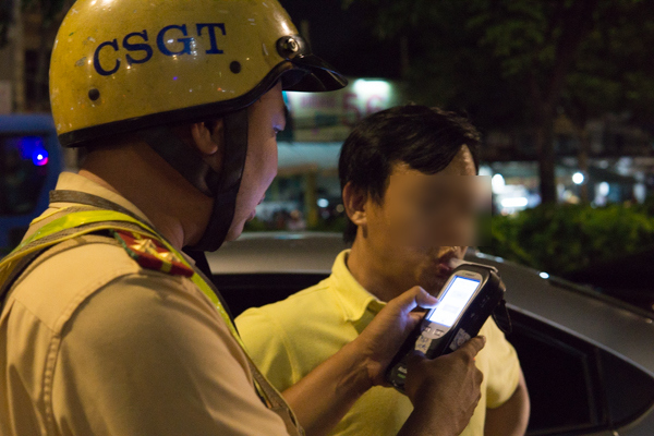 Một tài xế phải xuống xe để tiếp tục phép đo định lượng bằng máy thổi kiểm tra nồng độ cồn chuyên dụng
