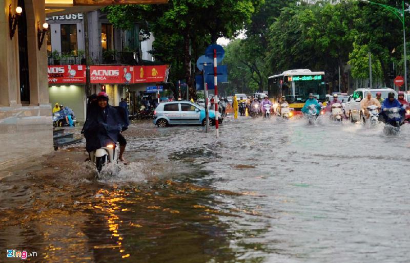 Xe máy đi trên vỉa hè sát Trung tâm thương mại vẫn bị ngập trong nước. Ảnh: 