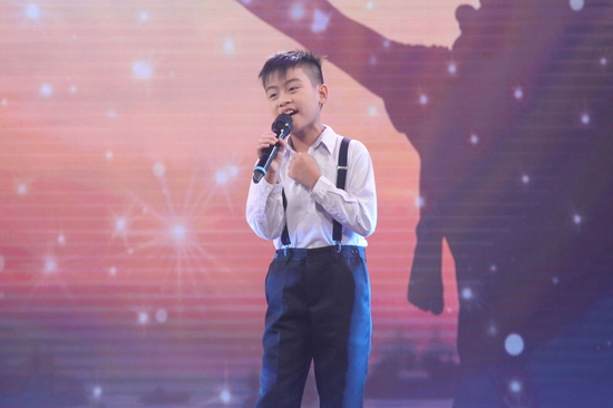 Tiếp đến, Tấn Bảo mang đến sân khấu ca khúc Ba kể con nghe của nhạc sĩ Nguyễn Hải Phong. Xuất hiện trong bộ trang phục như những thư sinh ngày xưa, cậu bé thể hiện ca khúc đầy nhẹ nhàng, truyền cảm khiến Cẩm Ly ngồi ở hàng ghế khán giả liên tục ngân nga hát theo. 