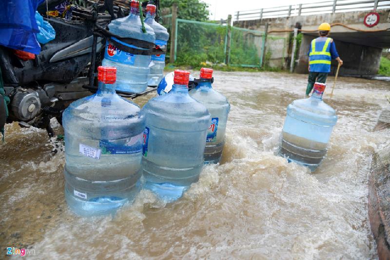 Một người chở nước lọc giao khách đi qua đây thì xe máy bị hỏng. Lái xe phải đỗ lại tháo bỏ hết các bình đặt xuống giữa dòng nước chảy.