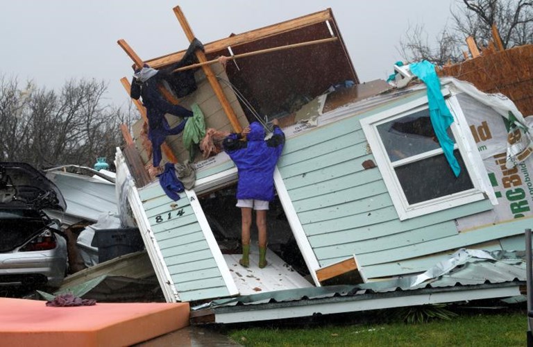Người phụ nữ tìm những vật dụng còn dùng được trong ngôi nhà tan hoang ở Fulton. Ảnh: Reuters.