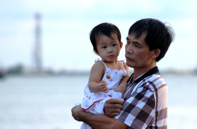 Tranh thủ thời gian chờ phà, bé gái được người thân bế ra bờ sông Lạch Huyện hóng gió.